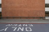 a red brick wall and sidewalk with an exit sign for people to walk around it