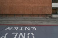 a red brick wall and sidewalk with an exit sign for people to walk around it