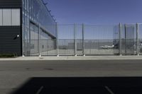 the parking area in the airport with a fenced entrance and air plane parked on the runway