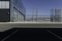 the parking area in the airport with a fenced entrance and air plane parked on the runway