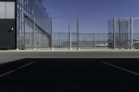 the parking area in the airport with a fenced entrance and air plane parked on the runway