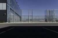 the parking area in the airport with a fenced entrance and air plane parked on the runway