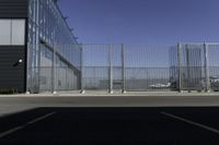 the parking area in the airport with a fenced entrance and air plane parked on the runway