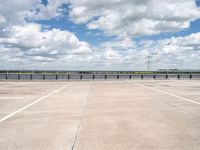 a wide expanse of parking spaces on top of a building with a cloudy blue sky