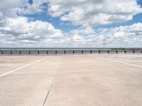 a wide expanse of parking spaces on top of a building with a cloudy blue sky