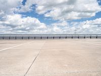 a wide expanse of parking spaces on top of a building with a cloudy blue sky