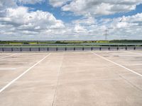 a wide expanse of parking spaces on top of a building with a cloudy blue sky