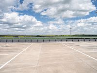 a wide expanse of parking spaces on top of a building with a cloudy blue sky