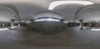 a fish eye lens image of a room full of concrete columns with a door leading into an empty building