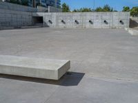 the empty parking lot in front of a wall with apartment buildings on it and a skateboarder on a ramp