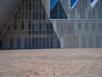 a white building with several steps and large glass panels in the facade is a mosaic that depicts a man