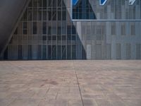 a white building with several steps and large glass panels in the facade is a mosaic that depicts a man