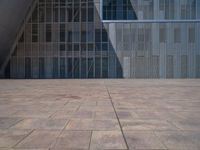 a white building with several steps and large glass panels in the facade is a mosaic that depicts a man