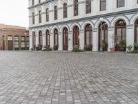 the sidewalk in front of the building is cobblestone and the clock has been set