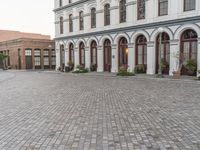 the sidewalk in front of the building is cobblestone and the clock has been set