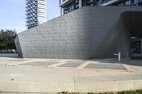 the side of an unfinished concrete building on a sidewalk with a parking meter attached to it