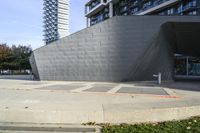 the side of an unfinished concrete building on a sidewalk with a parking meter attached to it