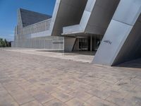 a white building with several steps and large glass panels in the facade is a mosaic that depicts a man