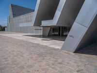 a white building with several steps and large glass panels in the facade is a mosaic that depicts a man