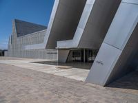 a white building with several steps and large glass panels in the facade is a mosaic that depicts a man