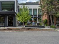 street corner with tree on the corner of the corner and a building behind it that is surrounded by multiple windows and a perforated brown lattice