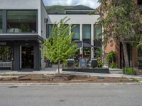 street corner with tree on the corner of the corner and a building behind it that is surrounded by multiple windows and a perforated brown lattice