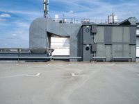 a building with air conditioners and some other things behind it on the roof of a large metal structure