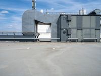 a building with air conditioners and some other things behind it on the roof of a large metal structure