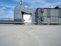 a building with air conditioners and some other things behind it on the roof of a large metal structure