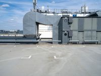 a building with air conditioners and some other things behind it on the roof of a large metal structure