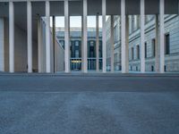 empty street lined with cement buildings next to a tall building with a staircase up to it