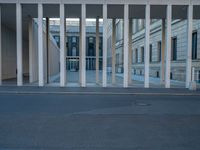 empty street lined with cement buildings next to a tall building with a staircase up to it