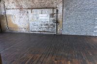 an old wooden floor with wood planks and a brick wall behind it and an open door