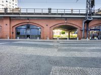 an outdoor area with a bridge and cars parked in front of it and two sets of columns