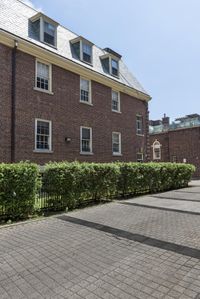 the brick buildings are located in front of some bushes and lawns as well as the roof line