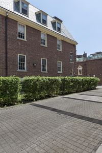 the brick buildings are located in front of some bushes and lawns as well as the roof line