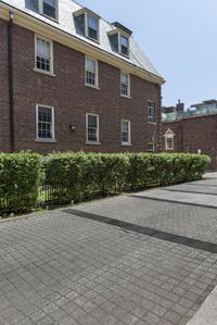 the brick buildings are located in front of some bushes and lawns as well as the roof line