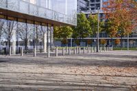 a row of benches that are on the sidewalk in front of a building with many trees