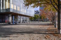 a row of benches that are on the sidewalk in front of a building with many trees