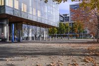 a row of benches that are on the sidewalk in front of a building with many trees