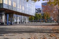 a row of benches that are on the sidewalk in front of a building with many trees