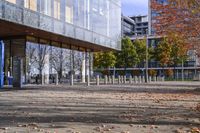 a row of benches that are on the sidewalk in front of a building with many trees