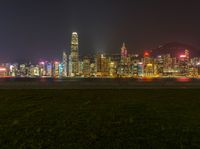 a cityscape at night as the lights of skyscrapers shine on the hills