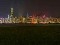 a cityscape at night as the lights of skyscrapers shine on the hills