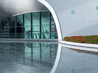 the reflection in the pool is of the building's facade, which appears as a curved, white wall