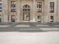 the reflection of the two people on a road in front of a tall building with a door