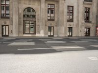 the reflection of the two people on a road in front of a tall building with a door