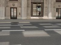 the reflection of the two people on a road in front of a tall building with a door