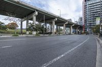 the empty roadway below an overpass in the city is gray and clean for vehicles