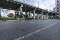 the empty roadway below an overpass in the city is gray and clean for vehicles